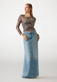 Gonna in denim lunga di colore azzurro chiaro con taglio dritto. Top a maniche lunghe in stampa serpente marrone con scollatura quadrata e dettagli arricciati.