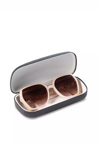 Okulary przeciwsłoneczne z jasnobeżową oprawką i ciemnymi soczewkami, spoczywające w czarnym teksturowanym etui z szarym wnętrzem i wkładką z materiału do czyszczenia.