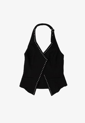 Veste noire à col halter ornée de clous argentés sur les bords et d’une lanière avec boucle au niveau du cou, avec une taille cintrée et deux poches avant.