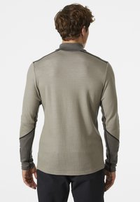 Camisa de manga larga en gris claro con detalles en gris oscuro. Presenta un tejido texturizado, un cuello y costuras en contraste a lo largo de las mangas.
