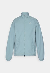 Chaqueta azul clara con cremallera, hecha de un tejido suave, con un cuello alto, bolsillos laterales y un logo blanco en el pecho. Presenta acentos de patrón de puntos.