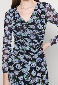 Schwarzes Kleid mit langen, durchsichtigen Ärmeln, das ein florales Muster in Blau und Grün zeigt, mit strukturiertem Raffen und einem tiefen V-Ausschnitt.