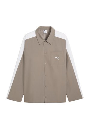 Beige blouse met lange mouwen en knopen, witte strepen op de schouders en mouwen, een borstzak en een Puma-logo op het zakje.