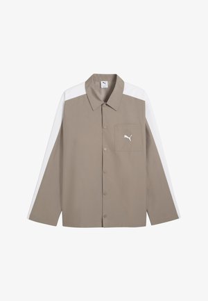 Beżowa koszula na długi rękaw na guziki, z białymi paskami na ramionach i rękawach, kieszonką na piersi oraz logo Puma na kieszeni.