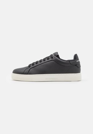 Baskets basses en cuir noir avec lacets noirs, semelle blanche et logo de la marque sur le talon et la semelle sur fond blanc.