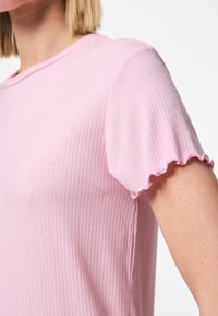 Camiseta de rayas rosa con mangas cortas y volantes, y un cuello redondo. Textura suave, diseño ajustado, estilo minimalista.