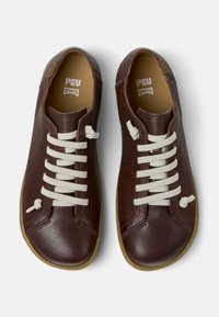 Bruna läderskor med beigefärgade snören, rundad tå och minimal sömnadsdetalj. Gummisula och Camper-märke på innersulan.