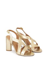 Gouden metallic slingback sandalen met gekruiste banden, open teen en een blokhak. Gladde textuur met een glanzende afwerking. Verstelbare gesp.