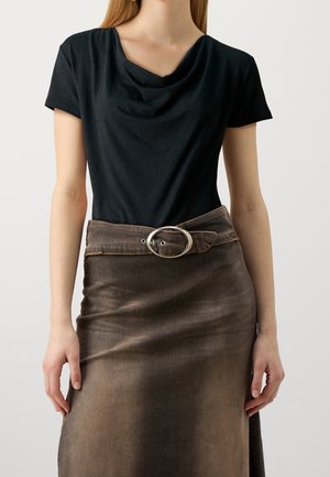 Czarny top z krótkim rękawem i drapowanym dekoltem, połączony z brązową spódnicą z szerokim paskiem i okrągłą srebrną sprzączką.