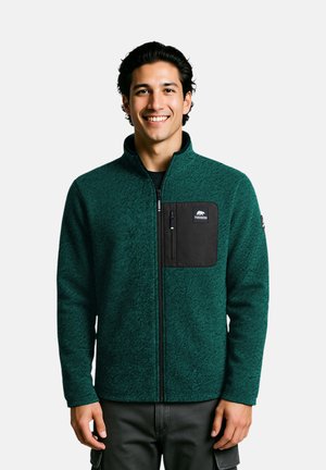 Türkise Fleecejacke mit hohem Kragen und schwarzem, mit Reißverschluss versehenem Brusttasche, versehen mit einer strukturierten Oberfläche und vorderem Reißverschluss.