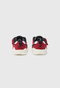 Sneaker rosse e nere con una parte superiore texturizzata, dettagli in rete e una chiusura in velcro. Presentano una suola in gomma bianca e il marchio Nike sul retro.
