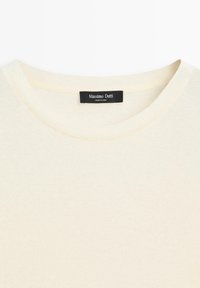 Krémový bavlněný svetr s kulatým výstřihem. Obsahuje černou značkovou etiketu přišitou uvnitř. Hladká textura, jednoduchý design.