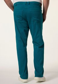 Pantalones de tela elástica color verde azulado con pierna recta, que cuentan con dos bolsillos traseros y lazos para cinturón, combinados con zapatos blancos.