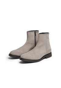 Botas de tobillo de ante gris con cremallera lateral, punta redondeada y suela de goma plana. Textura suave y diseño minimalista sin adornos visibles.