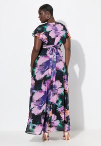 Robe maxi en tissu noir avec un grand imprimé floral violet et vert. Présente des manches courtes à volants et un détail de taille nouée.