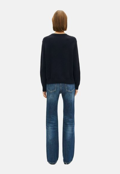 Suéter de punto navy con cuello redondo, combinado con jeans rectos de color azul claro. Textura suave; ajuste casual.