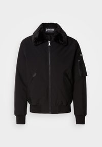 Black bomber jacket made from soft fabric with a fur collar, front zip closure, side pockets, and a utility pocket on the sleeve.