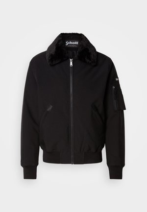 Chaqueta bomber negra hecha de un tejido suave, con cuello de piel, cierre delantero con cremallera, bolsillos laterales y un bolsillo utilitario en la manga.