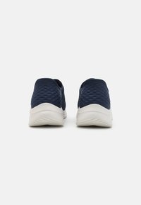 Navy Slip-On-Schuhe mit einer strukturierten Oberseite und weißen Gummisohlen, die ein abgerundetes Design und eine gepolsterte Ferse für Komfort bieten.