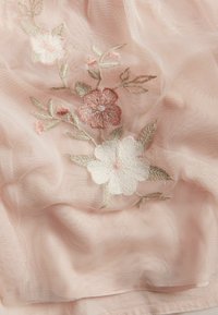 Helles rosa, durchscheinendes Gewebe mit filigraner floraler Stickerei in Weiß-, Rosa- und Grüntönen, kombiniert mit einer weichen Textur und zarten Details.