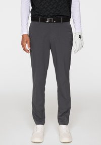 Szare spodnie golfowe wykonane z lekkiego materiału, z lekkim zwężonym krojem, subtelną teksturą i bocznymi kieszeniami. W zestawie z czarnym paskiem i białymi butami.