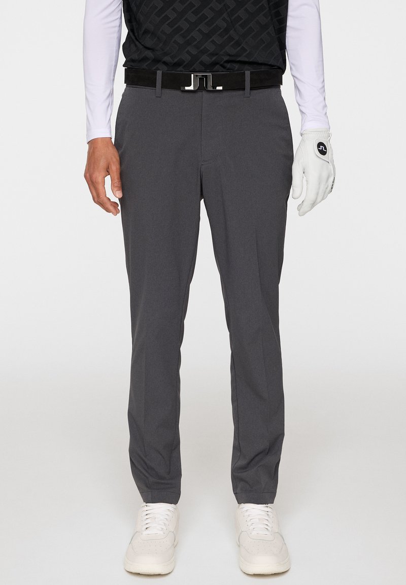Szare spodnie golfowe wykonane z lekkiego materiału, z lekkim zwężonym krojem, subtelną teksturą i bocznymi kieszeniami. W zestawie z czarnym paskiem i białymi butami.