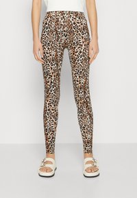 Luipaardprint legging met een aansluitend ontwerp, gladde textuur en een elastische tailleband. Gecombineerd met witte slippers.