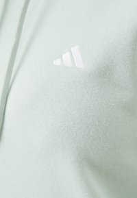 Hoodie atlético verde claro com textura suave. Apresenta um logótipo bordado branco com três linhas diagonais na área do peito esquerdo.