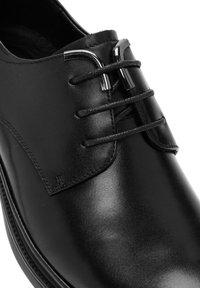 Zwarte leren jurk schoen met een gladde textuur, vetersluiting en metalen accenten bij de veters. Heeft een elegante, afgeronde neusvorm.