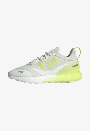 Chaussure de course blanche et gris clair avec accents jaune néon, dessus en mesh, semelle rembourrée, et fermeture à lacets, vue de côté sur fond blanc.