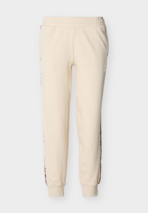 Pantalones jogger color crema con cintura elástica y puños acanalados, con paneles de estampado de leopardo en los lados exteriores de las piernas.