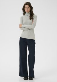 Helehall turtleneck-kampsun, mis on valmistatud pehmest kangast, on ühendatud tumedate laia säärega teksadega, luues lõdva silueti. Minimalistlik disain.