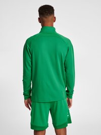 Grøn sportsjakke og shorts lavet af tekstureret stof. Jakken har en høj krave og lange ærmer.