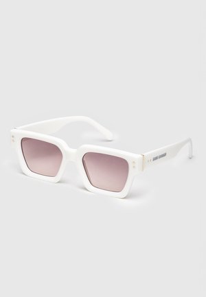 Lunettes de soleil rectangulaires blanches avec des montures épaisses et des verres dégradés roses, posées sur une surface unie.