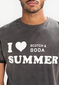 Grå bomulls t-shirt med rund hals, försedd med en vit grafisk design som säger "I ♥ SCOTCH & SODA SUMMER" i olika typsnitt.