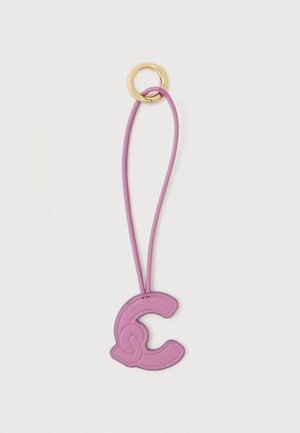 porte-clés en métal doré avec un cordon en cuir rose et un charme en cuir rose en forme de lettre "C" attaché sur fond blanc.
