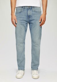 Jeans in denim azzurro chiaro con design a gamba dritta, stile a cinque tasche e un leggero effetto sbiadito. Abbinati a sneakers bianche.