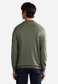 Grüner Strickpullover mit langen Ärmeln, Rundhalsausschnitt und gerippten Bündchen. Mit einem kleinen, dreifarbigen Logo-Detail am hinteren Halsauschnitt.