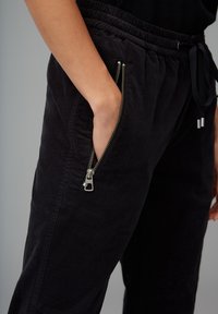 Zwarte corduroy joggerbroeken met een relaxte pasvorm, voorzien van een ritssluiting zak en een elastische tailleband met trekkoord voor verstelbaar comfort.