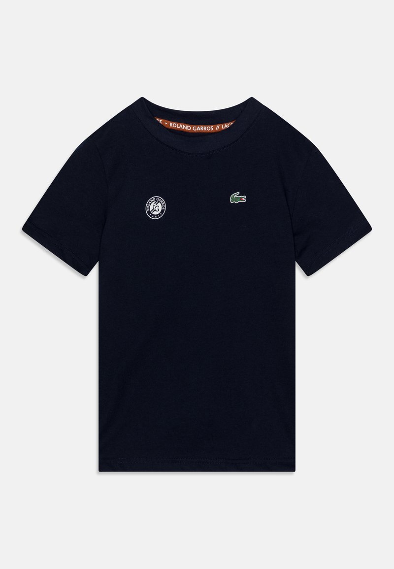 T-shirt à manches courtes bleu marine en coton, arborant un petit logo de crocodile vert et un emblème blanc de Roland Garros sur la poitrine.