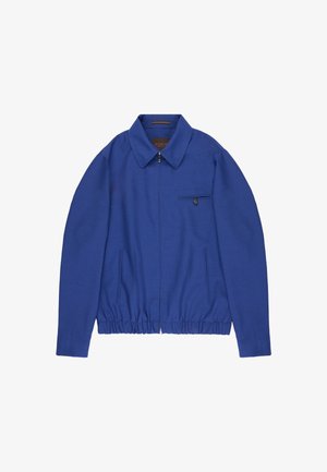 Chaqueta azul con cremallera, cuello puntiagudo, cintura elástica, dos bolsillos laterales y un pequeño bolsillo con botón en el pecho.