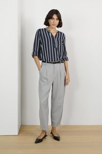 Blusa a rayas en azul marino y blanco con mangas enrolladas, combinada con pantalones de cintura alta en gris claro. Unos zapatos planos de punta negra completan el look.