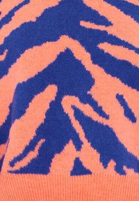 Maglione lavorato a maglia con un motivo a strisce di tigre in vivace corallo e blu navy, con una consistenza morbida e blocchi di colore a contrasto.