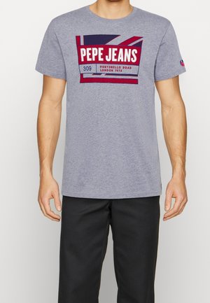 Grey short-sleeve t-shirt made of soft fabric featuring a bold printed logo. The design includes red and navy accents with a rectangular badge.