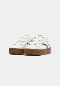 White sneakers with a smooth leather finish, brown rubber sole, and subtle black accent. Features round laces and embossed branding.