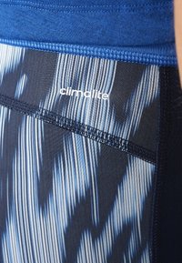 Climalite-Sportbekleidung verfügt über einen blauen Bund und ein gemustertes Stoffdesign in Blau und Schwarz, das vertikale Streifen und glatte Nähte zeigt.
