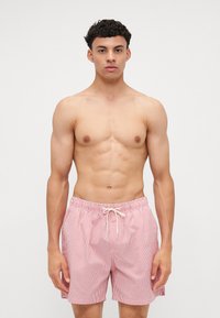 Κόκκινες και λευκές ριγέ μαγιό βερμούδες με ελαστική μέση και κορδόνι, που διαθέτουν άνετη εφαρμογή και ελαφρύ ύφασμα.