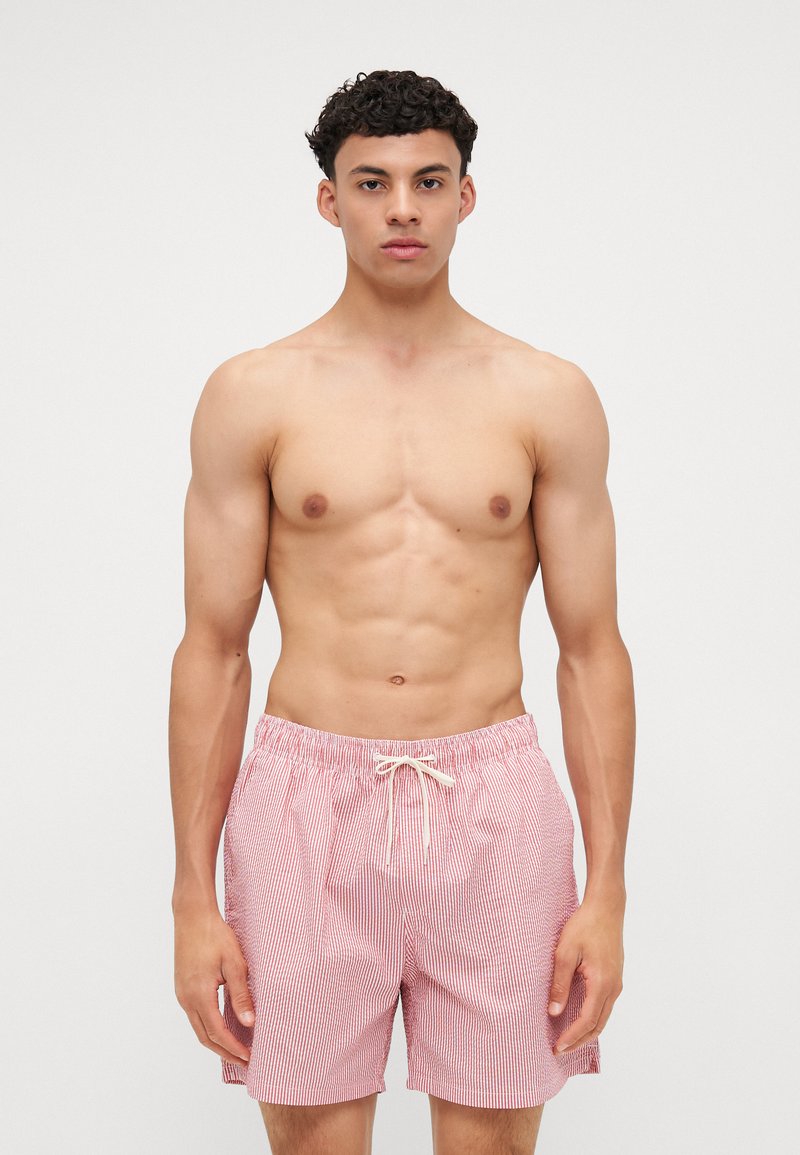 Κόκκινες και λευκές ριγέ μαγιό βερμούδες με ελαστική μέση και κορδόνι, που διαθέτουν άνετη εφαρμογή και ελαφρύ ύφασμα.