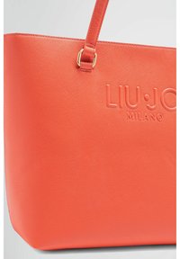 Borsa a tracolla arancione in materiale sintetico testurizzato, con logo in rilievo "LIU·JO MILANO", manico robusto e forma scolpita. Accenti in hardware dorato.