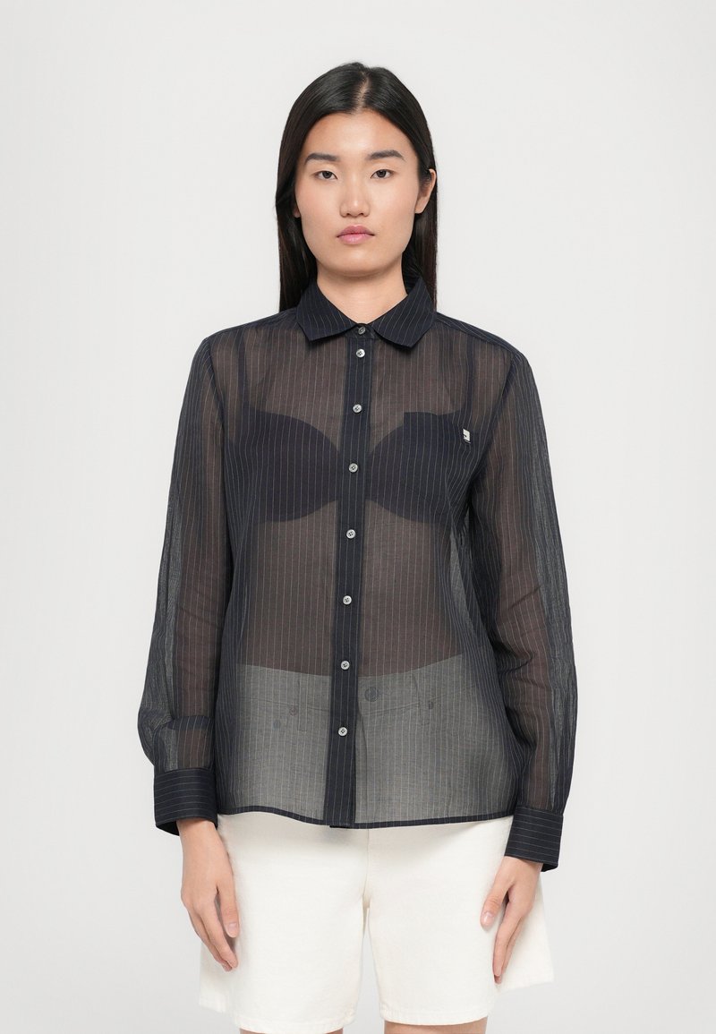 Sheer black button-up shirt with white vertical stripes, long sleeves, and a pointed collar. Features a small logo on the chest.